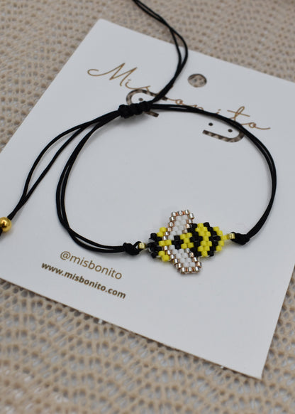 Black bracelet with bee-shaped charms on a branded card
