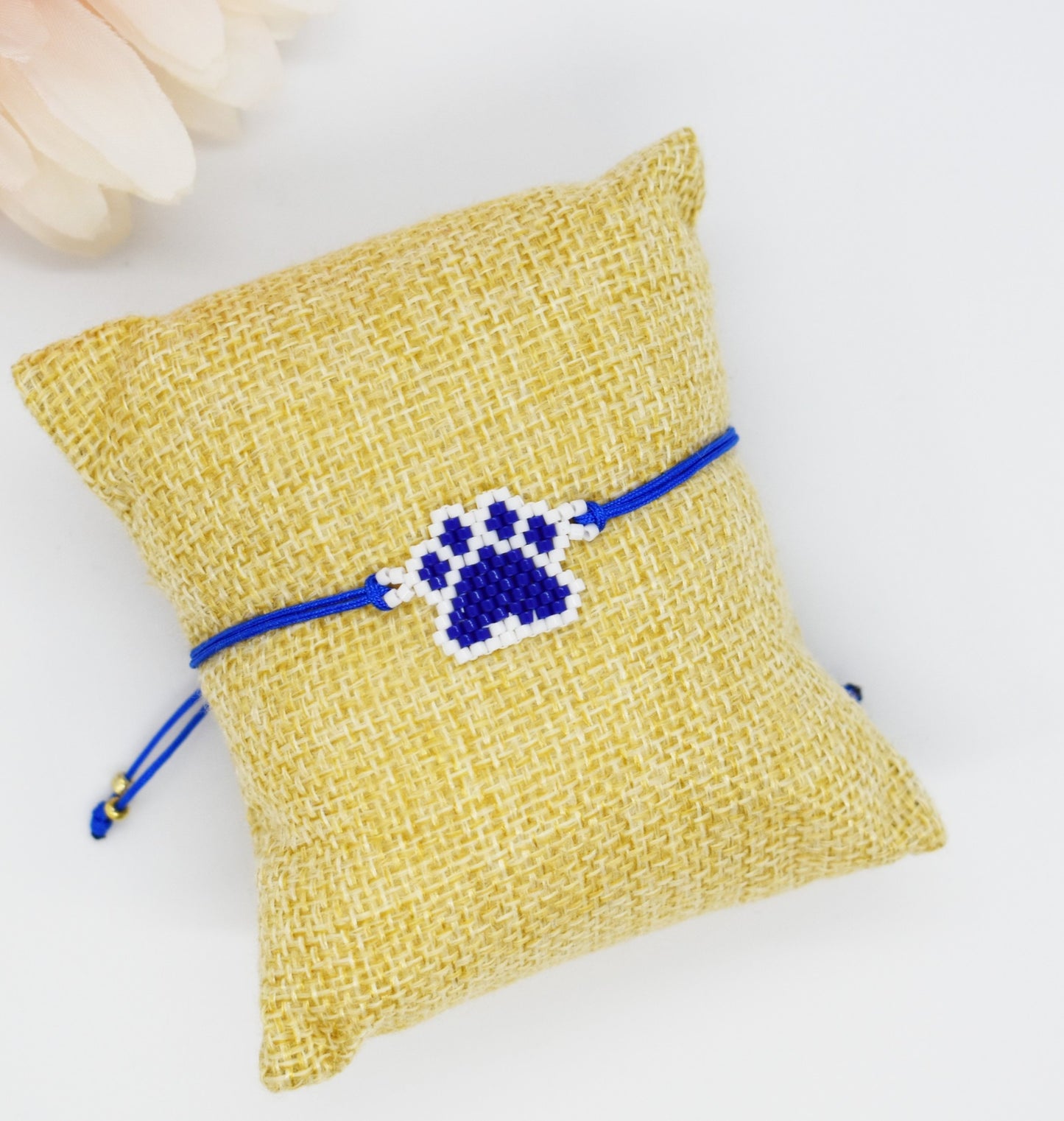 Blue beaded paw bracelet on a pillow