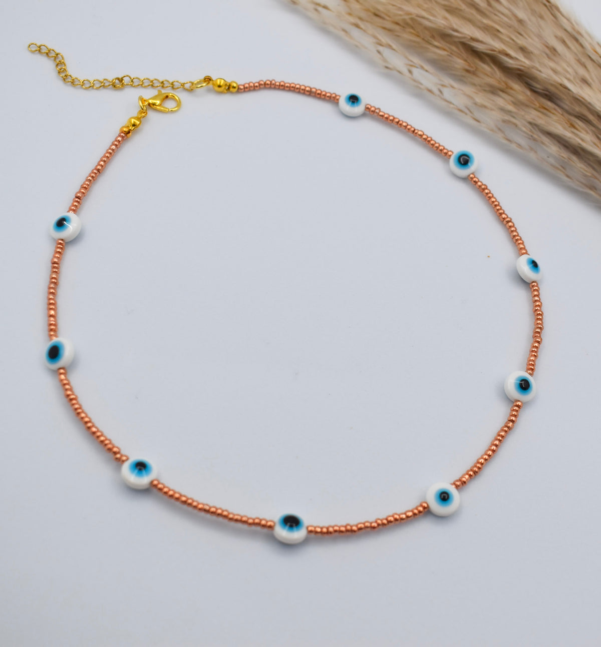 evil eye golden necklace on a white surface