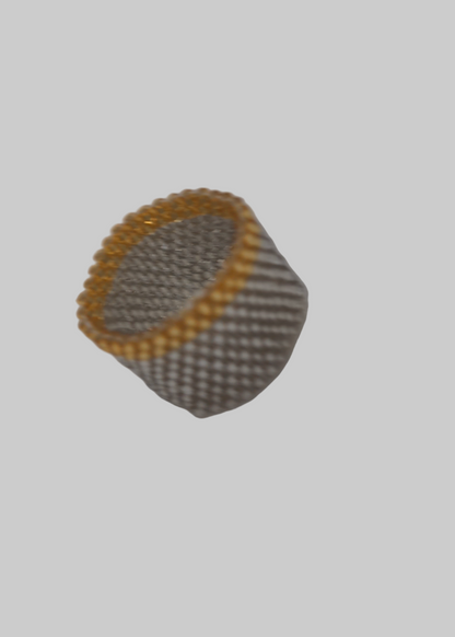 Round metallic object with yellow rim on a white surface