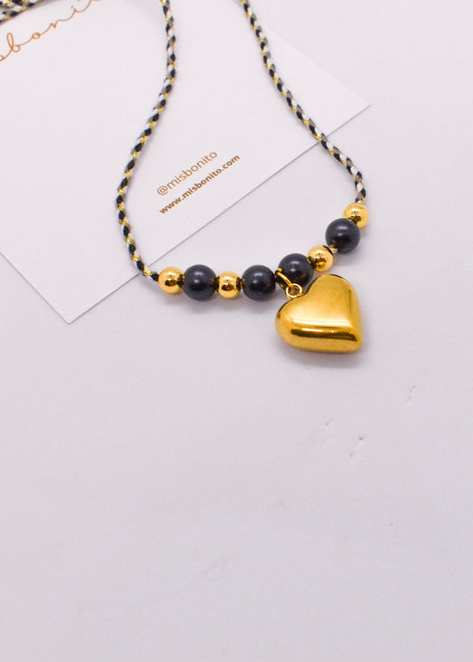 Necklace with gold heart pendant and black beads on a white background