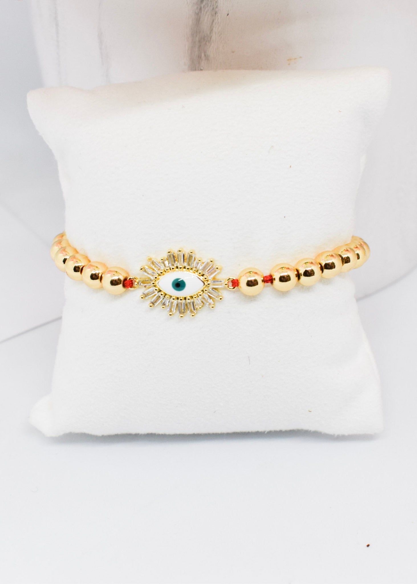 Gold bracelet with a central eye design on a white cushion