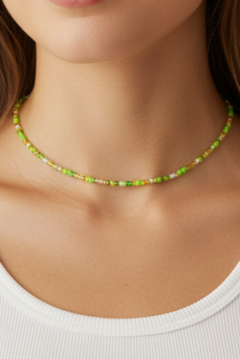 Woman wearing a white tank top and green beaded necklace against a beige background
