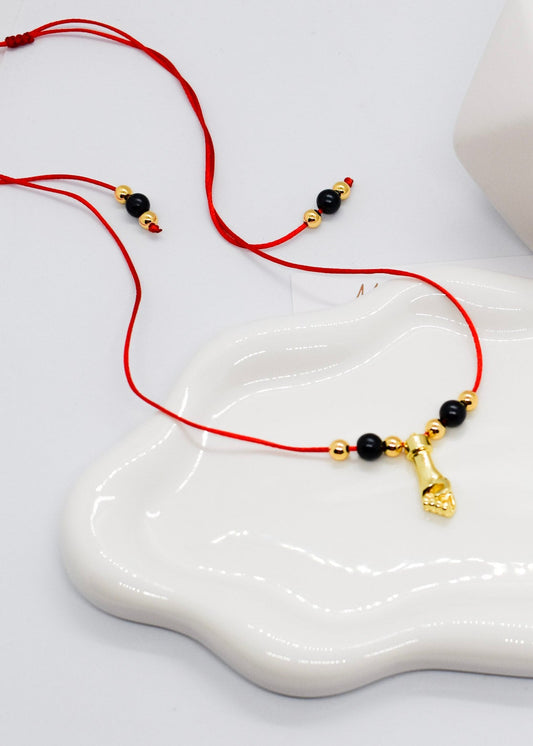 hand necklace on red nylon string on an irregular dish displayed