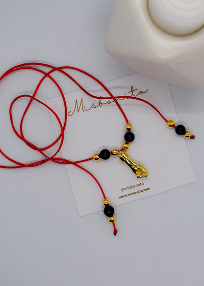 Red cord necklace with black and gold beads on a white card with 'Misbonito' branding.