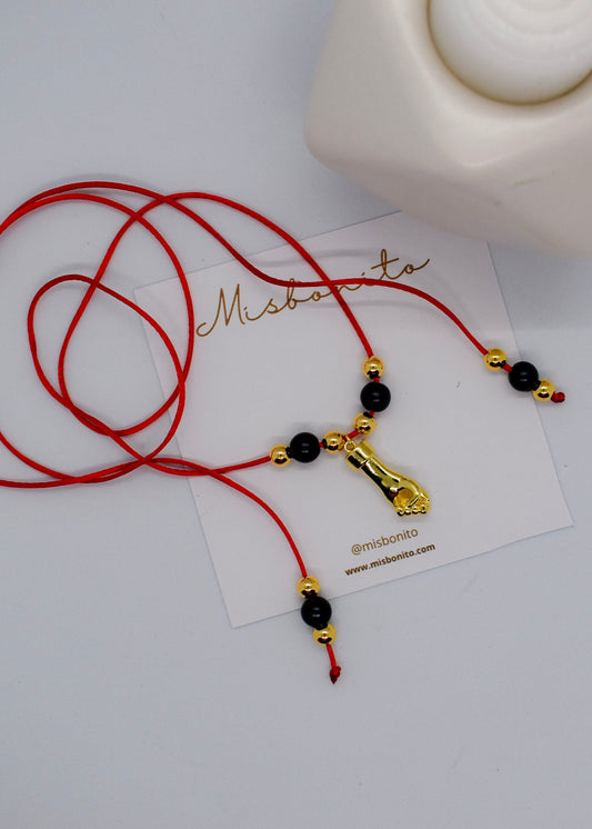 Red cord necklace with black and gold beads on a white card with 'Misbonito' branding.
