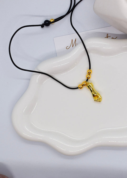 Gold pendant hand necklace on a white dish with a blurred background