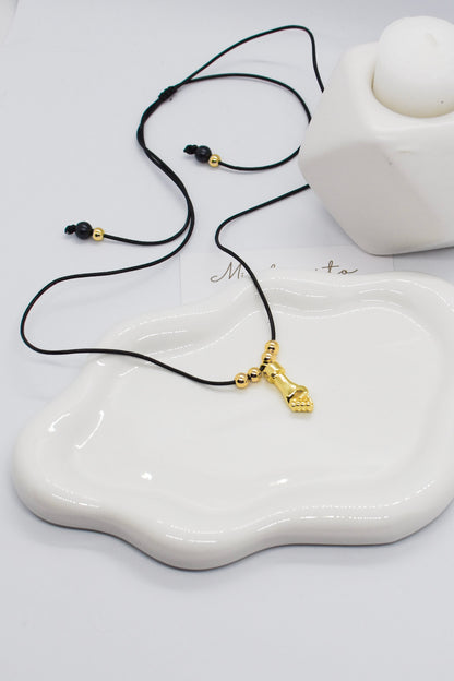 Necklace with a gold pendant on a white ceramic dish, with 'Minta' branding.
