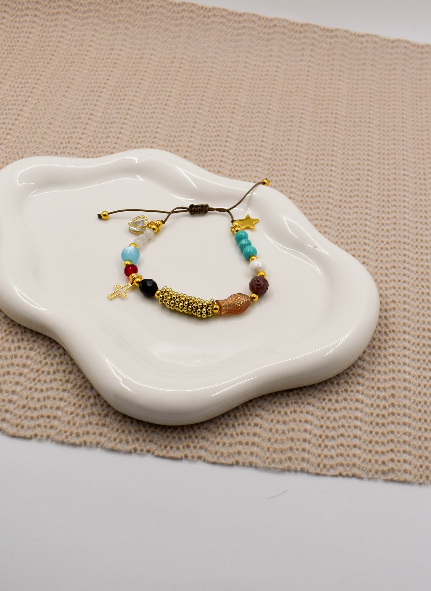 Bracelet with beads on a white dish on a textured surface