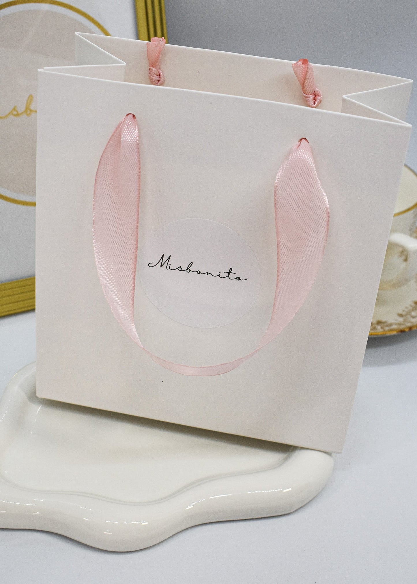 White gift bag with pink handles on a white surface