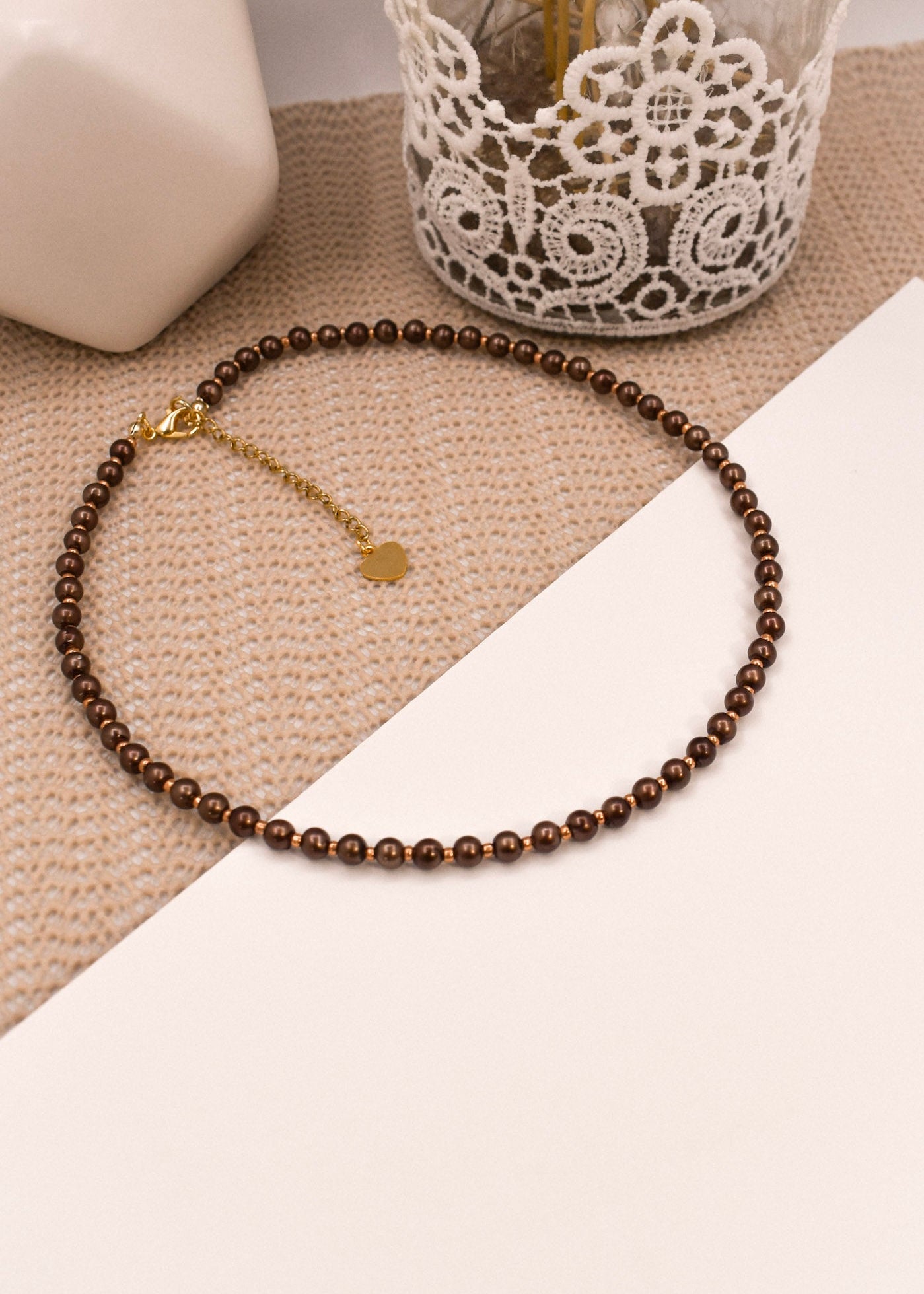 Brown beaded necklace with a gold clasp on a textured surface