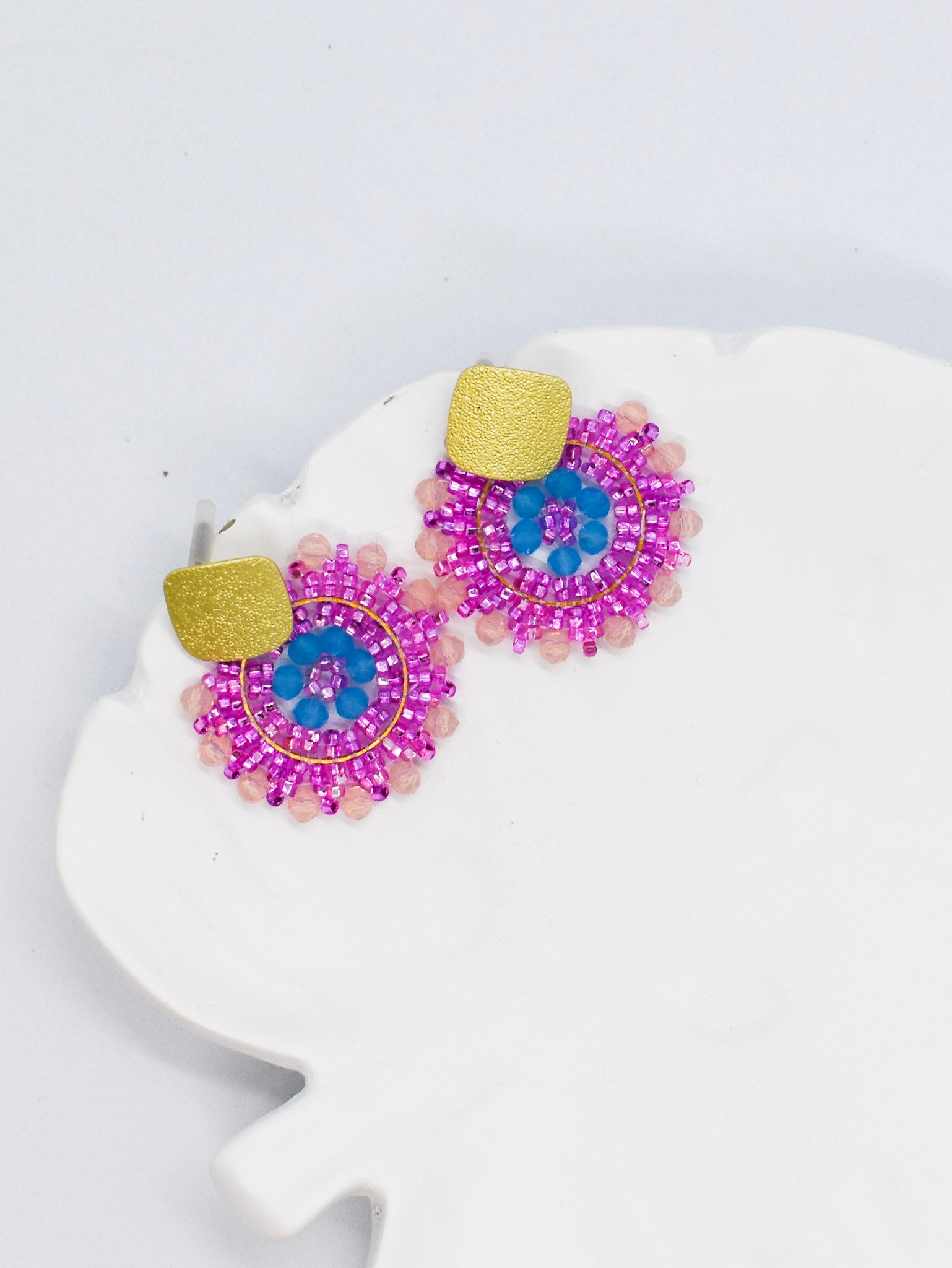 pink beaded round earrings on a white tray