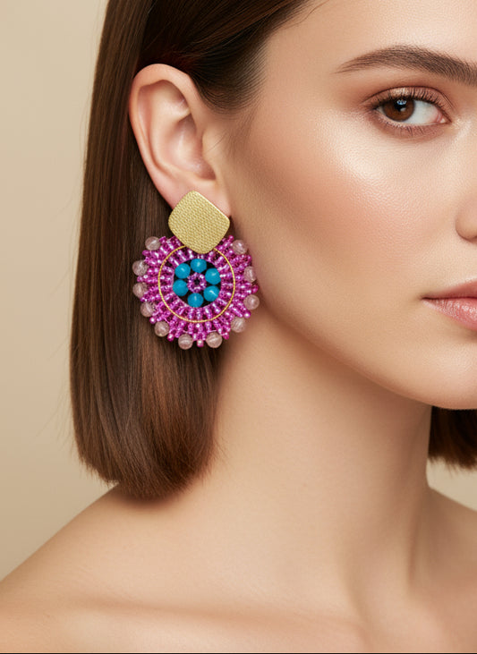 Ai model wearing a pair of beaded earrings with pink and blue design on a beige display box.