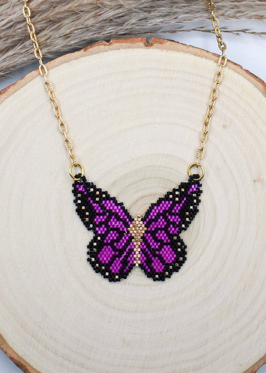 purple butterfly necklace on a wood background