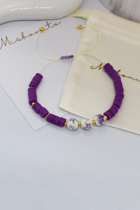 purple heishi bead with 3 beads with a pouch and a misbonito card