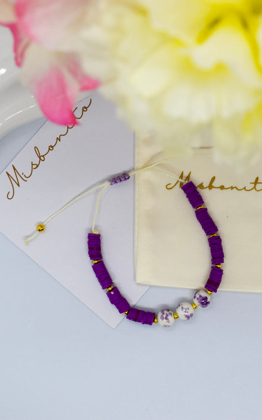 purple heishi bead with 3 beads on a misbonito branded card and pouch