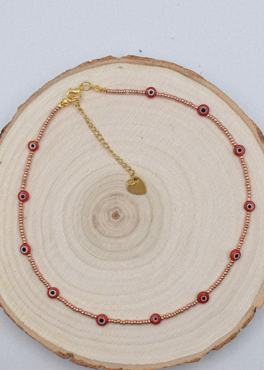 red and golden evil eye necklace choker on wood surface