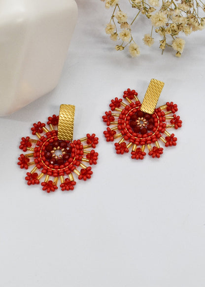 Red beaded earrings with gold accents on a white background