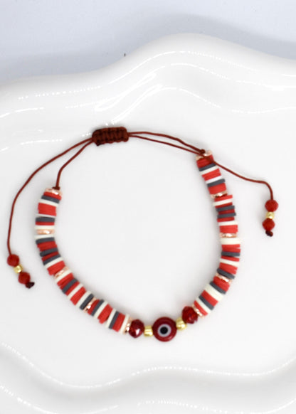red heishi beads bracelet with evil eye bead on a white tray