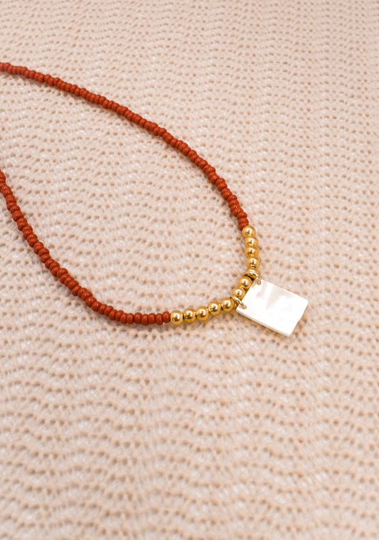 Necklace with red and gold beads on a beige fabric background