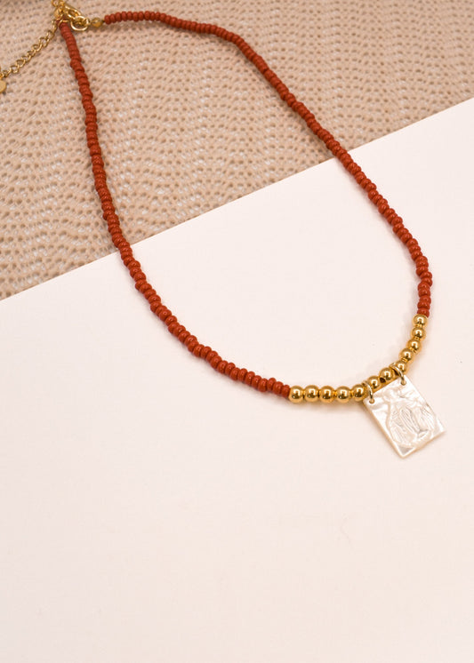 Necklace with red beads and gold accents on a white surface