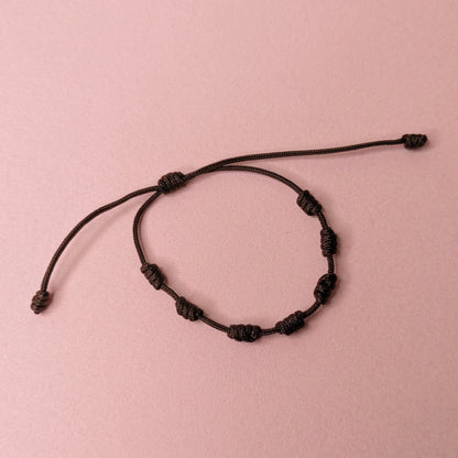 A dark brown beaded cord bracelet with adjustable sliding knots, displayed on a plain white surface.