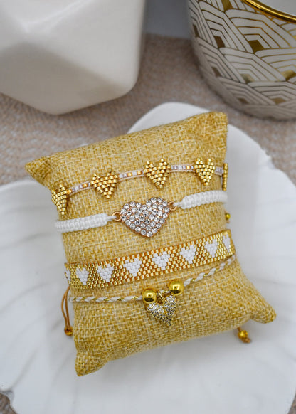 Set of gold and white bracelets on a decorative yellow pillow with a blurred background