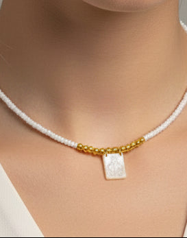 Necklace with white beads and gold accents on a textured surface