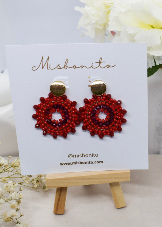 Red beaded earrings on a Misbonito card with flowers in the background