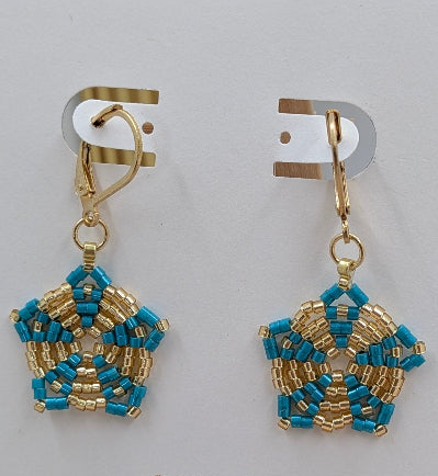 A pair of handmade beaded dangle earrings with gold-toned hooks and pentagonal star-shaped charms featuring turquoise and gold seed beads, displayed on a light gray background.