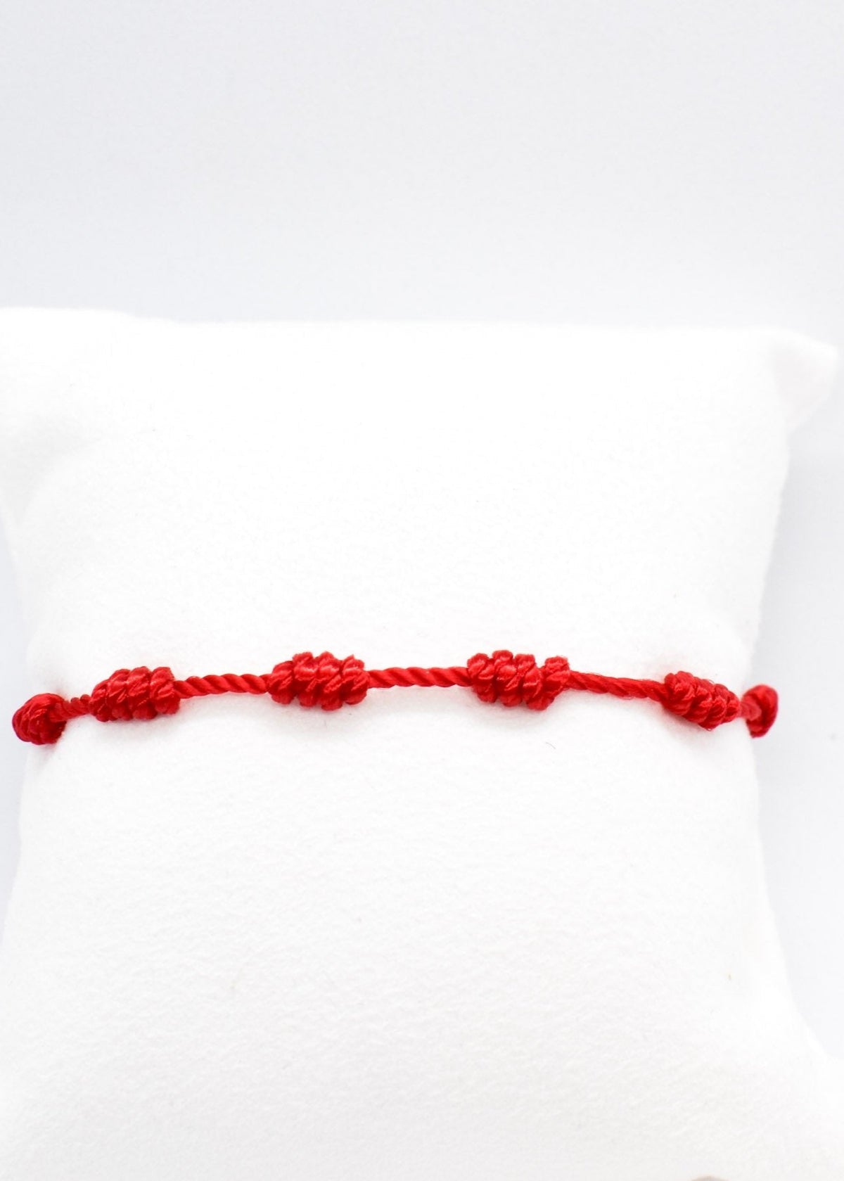 water resistant red string seven knots bracelet on a white pillow display