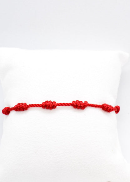 water resistant red string seven knots bracelet on a white pillow display