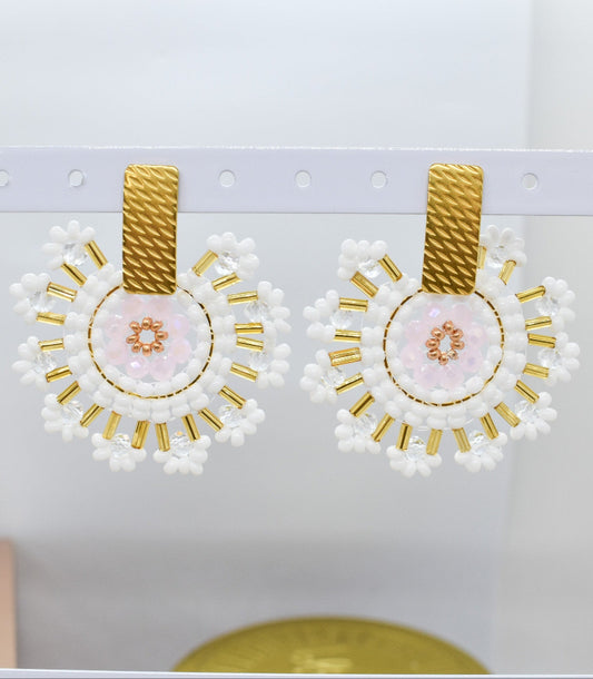 Pair of earrings with gold and white design on a light gray background